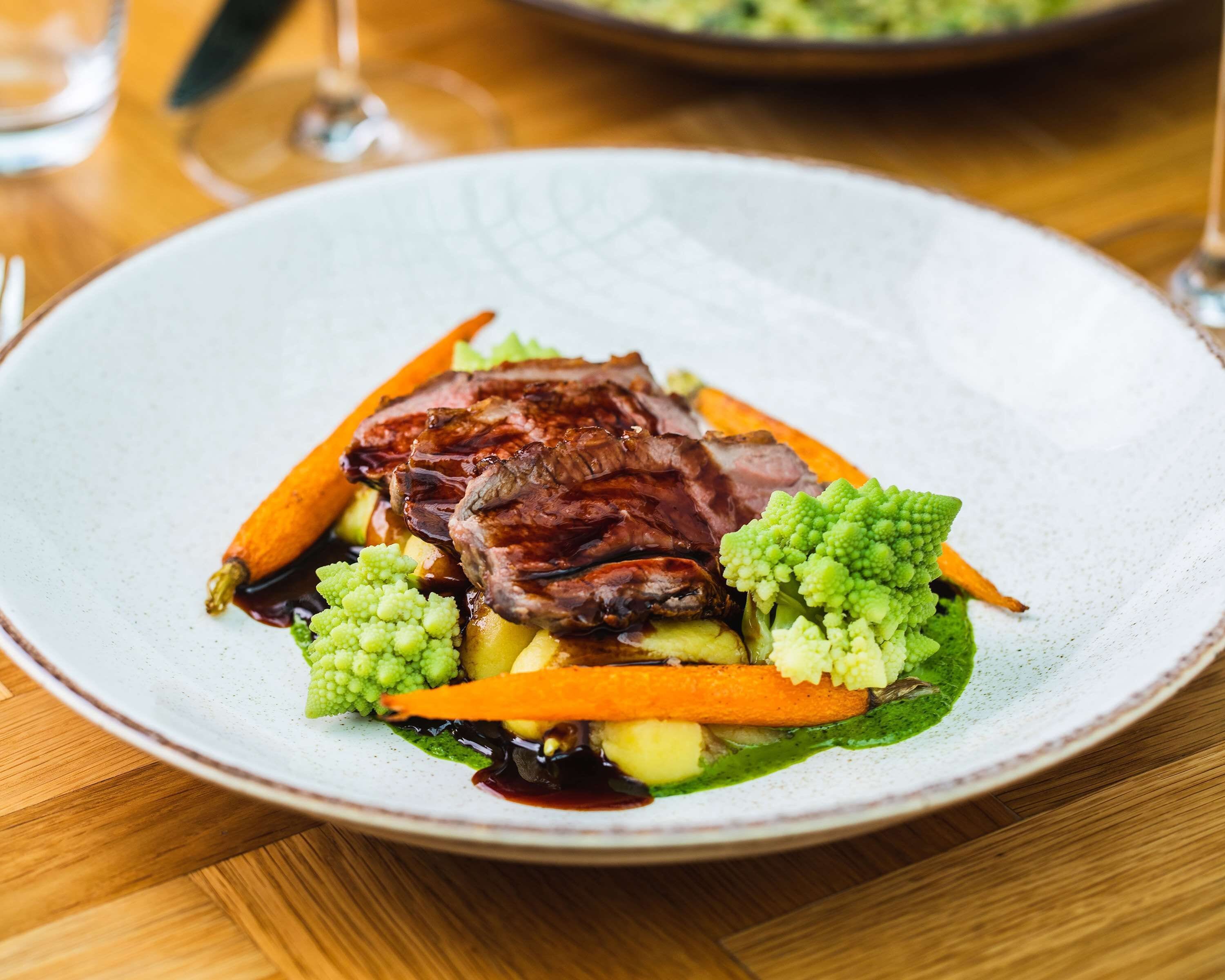 Un plato de comida con carne, verduras y salsa.