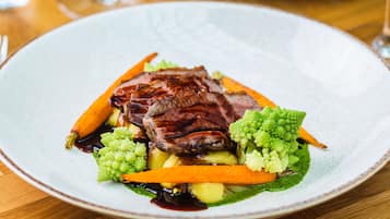 Un plato de comida con carne, verduras y salsa.