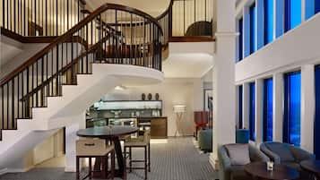 A spacious interior with a curved staircase, a dining area, and a seating area with large windows.