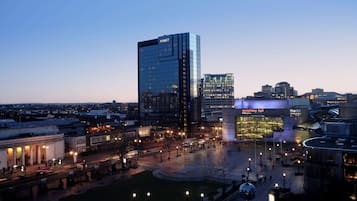 A modern hotel with a glass facade, a central courtyard, and a symphony hall nearby.