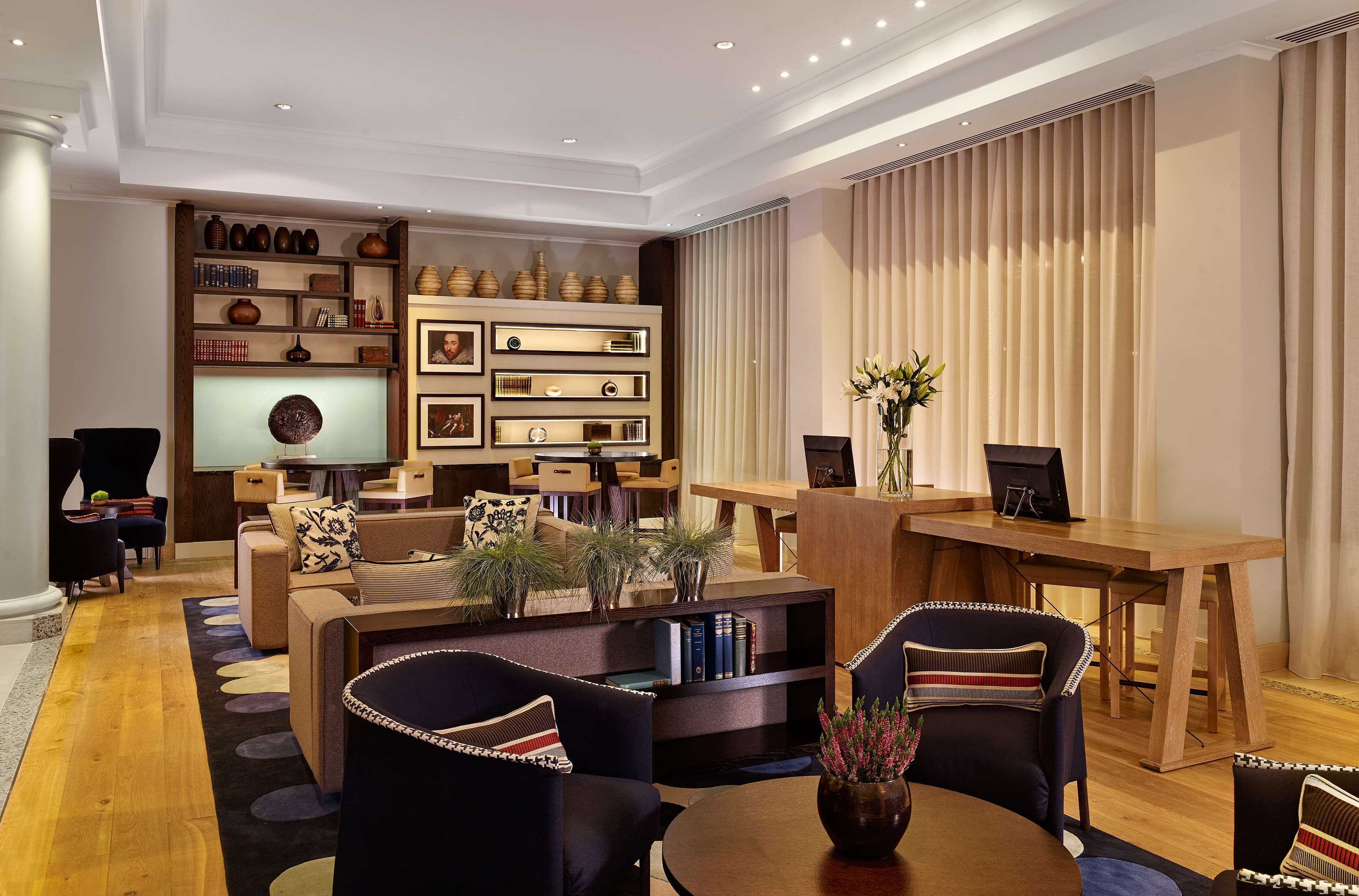 Ein modernes Wohnzimmer mit einer Couch, Sesseln, einem Couchtisch, einem Fernseher, einem Bücherregal und einem Essbereich.