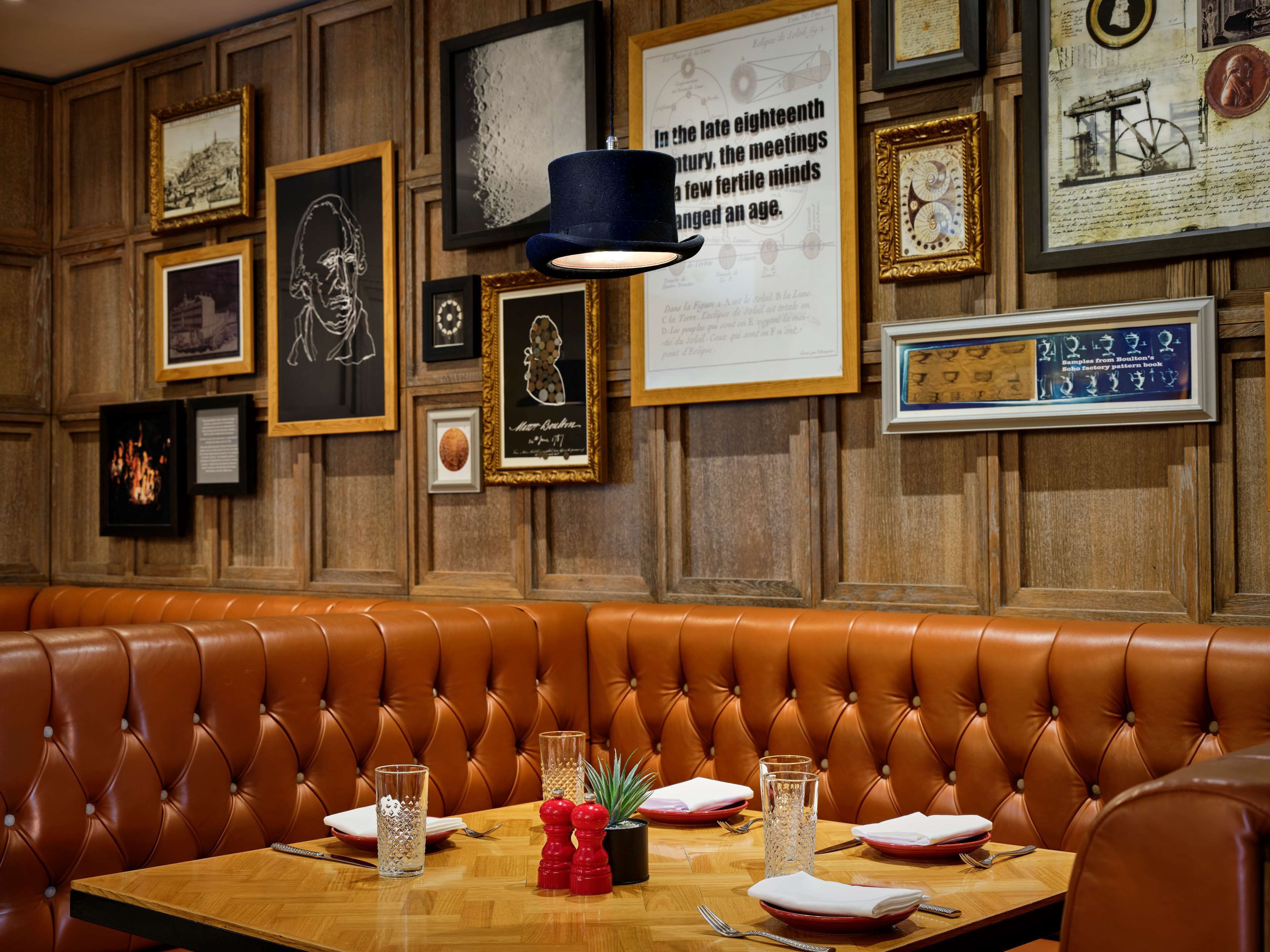 A restaurant with a wooden wall adorned with framed pictures and a tufted leather booth.