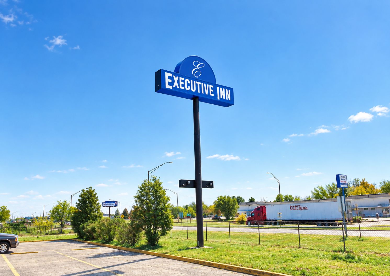 Un letrero azul para el Executive Inn, con logotipo, sobre un cielo despejado.