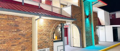 A building with a brick facade, a red awning, and a sign indicating an office.