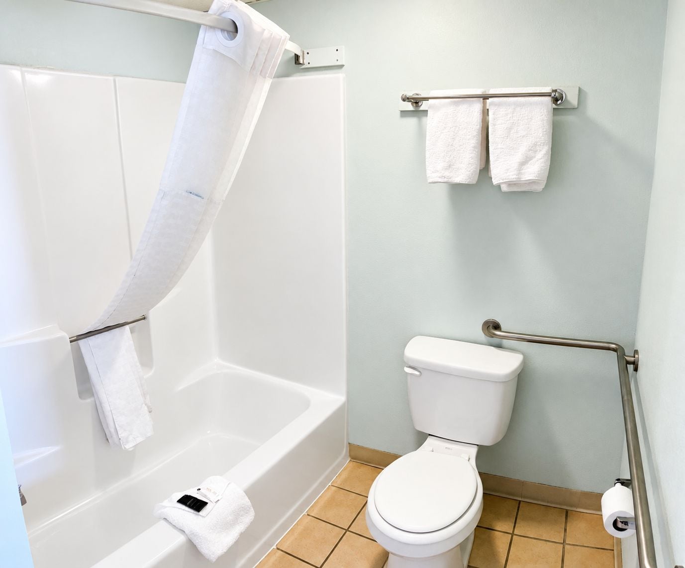 A bathroom with a bathtub, toilet, and towel rack.