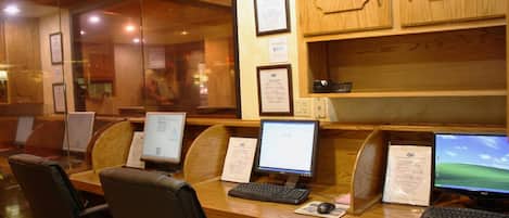 A computer lab with multiple workstations, wooden cabinets, and framed certificates on the wall.