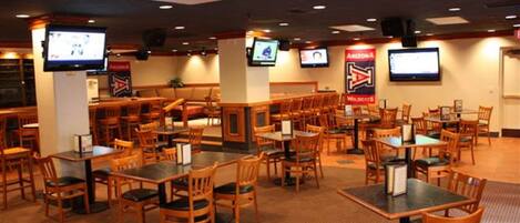 A restaurant with multiple tables and chairs, equipped with flat-screen TVs on the walls.