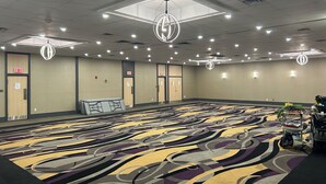 A hotel conference room with a patterned carpet, multiple exit doors, and ceiling lights. - Ramada by Wyndham Trenton (Quinte West)