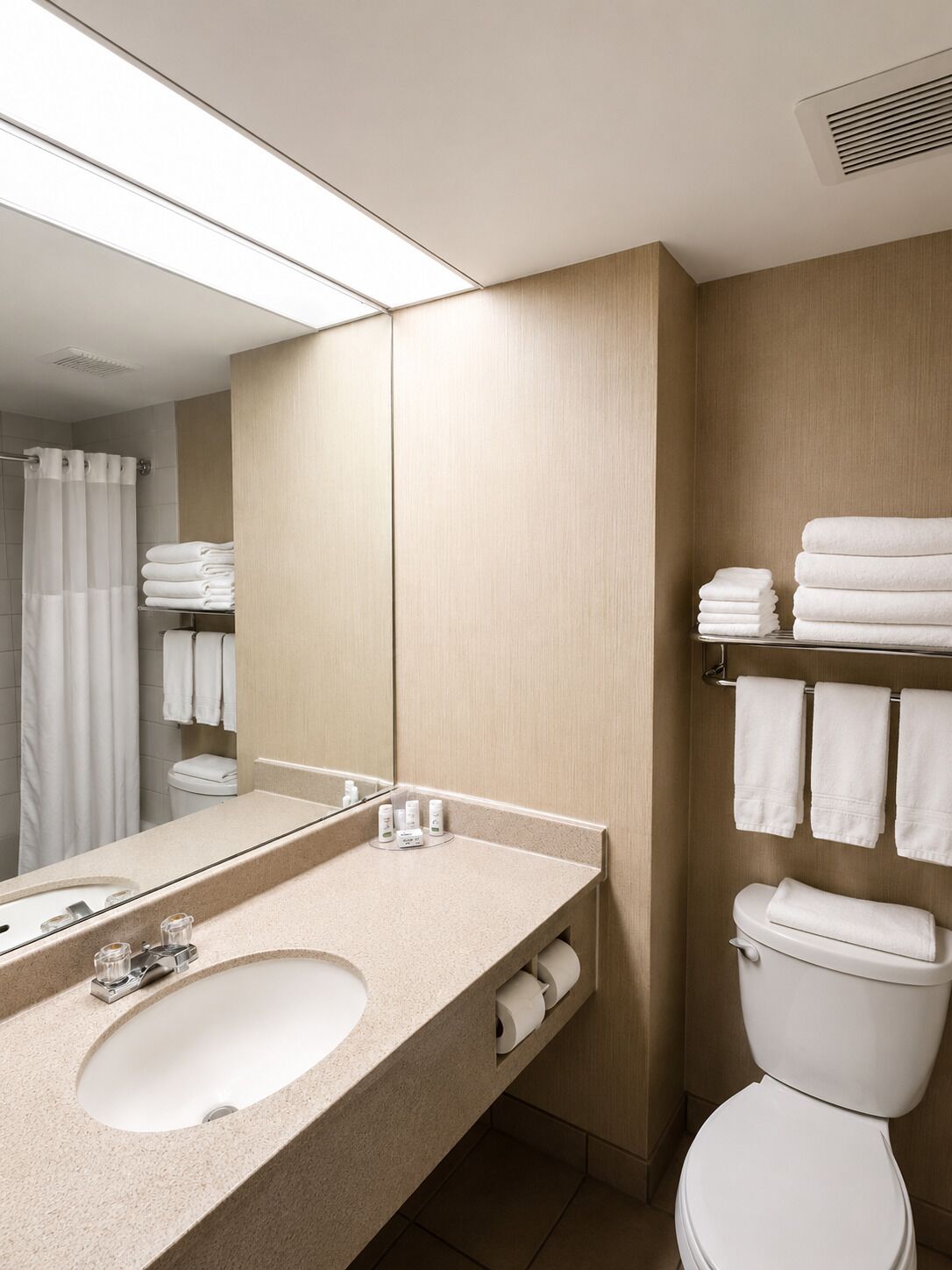 A modern bathroom with a sink, mirror, and toilet.
