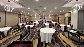 A conference room with round tables, chairs, and a podium. - Ramada by Wyndham Trenton (Quinte West)