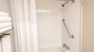 Un baño con bañera, ducha con cabezal de ducha de mano, barra de apoyo y toallero con toallas dobladas.
