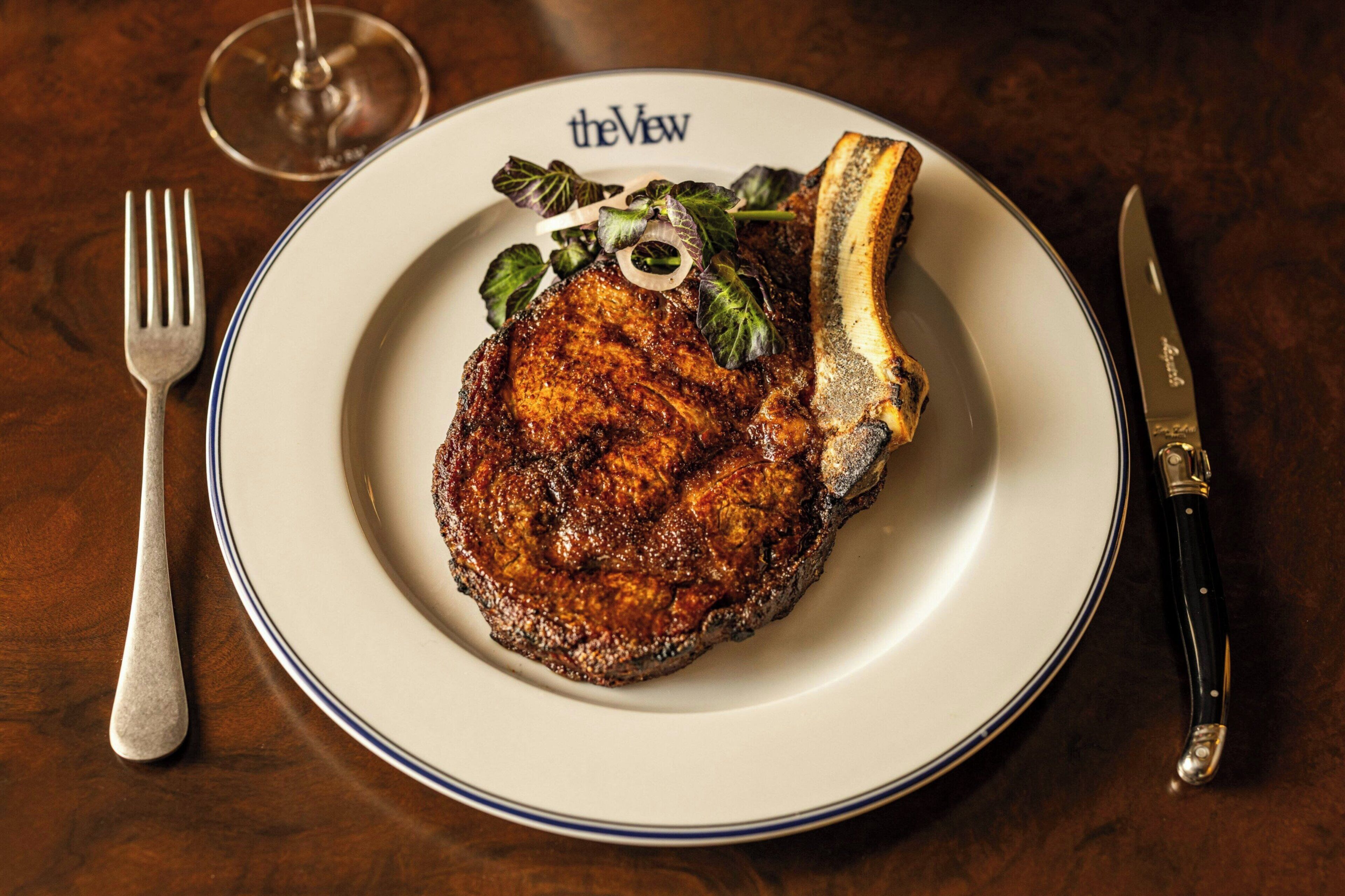 A plate with a steak and a knife on a table.