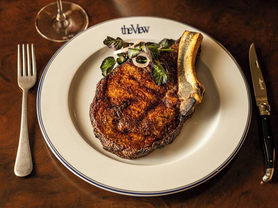 A plate with a steak and a knife on a table.