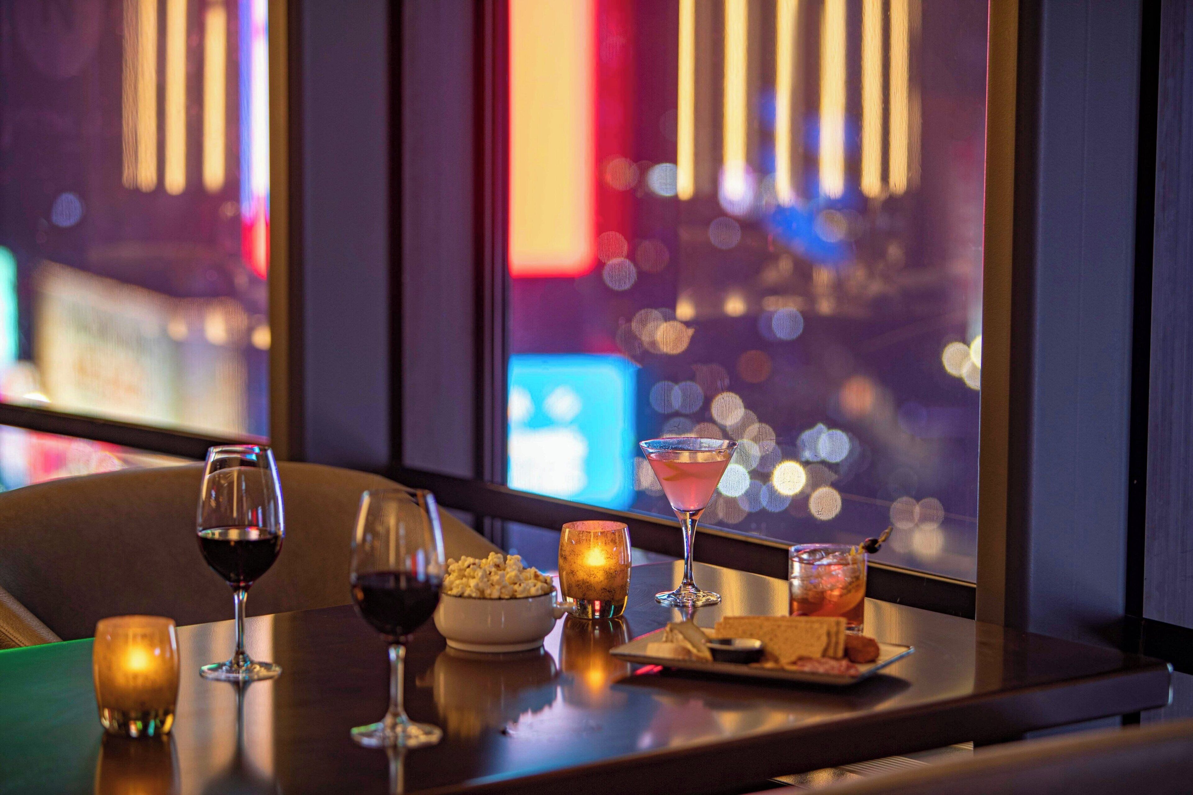 Eine Bar mit Blick auf die Stadt, eine Schüssel Popcorn und zwei Weingläser.