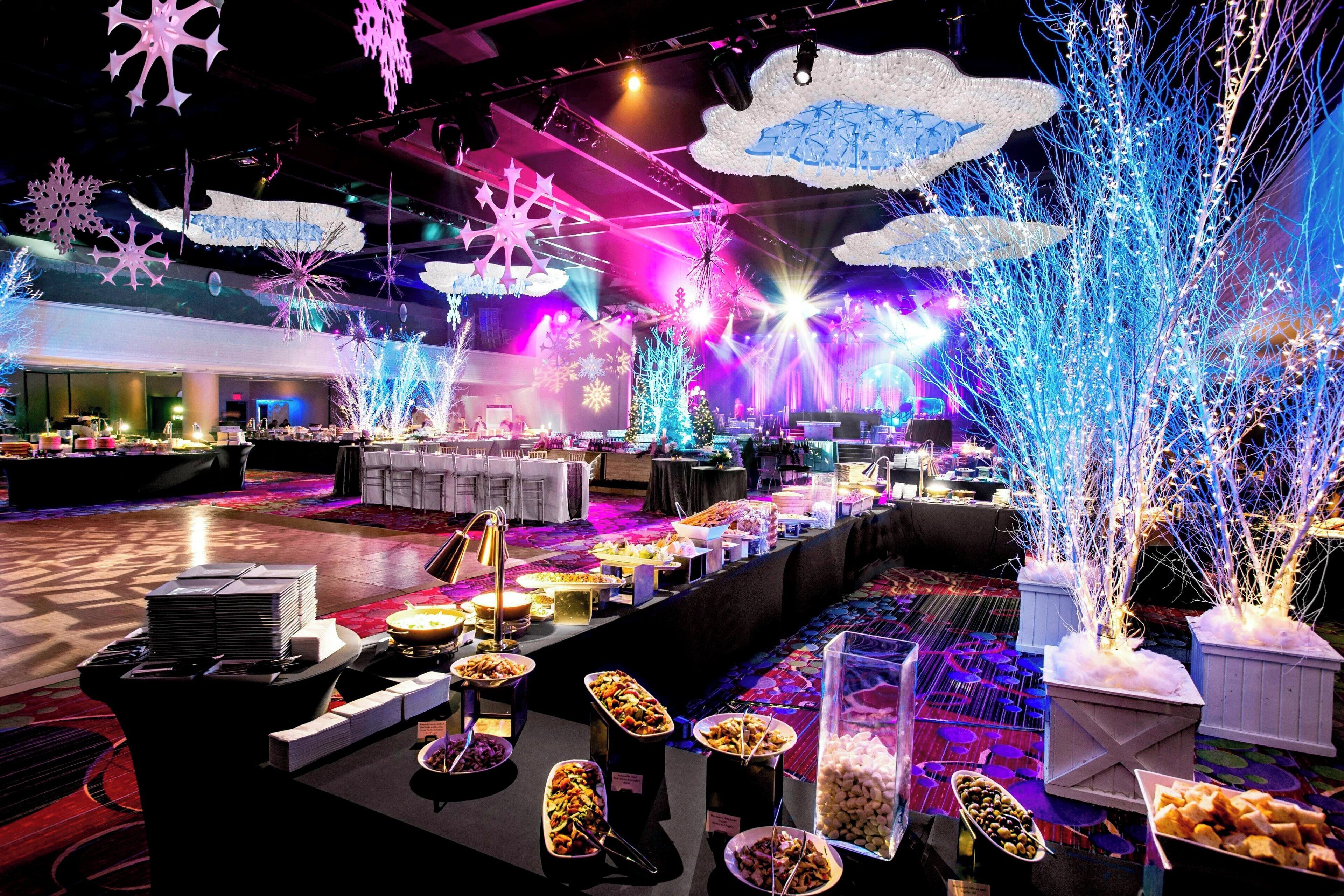 A buffet area with various food stations and decorative elements like snowflakes and illuminated trees.