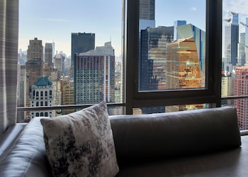 A modern restaurant with a central seating area, multiple tables, and a large window offering a city view. at New York Marriott Marquis