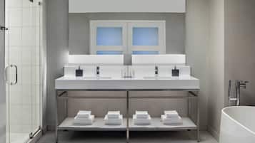A modern bathroom with a large mirror, two sinks, a shower, and a bathtub.