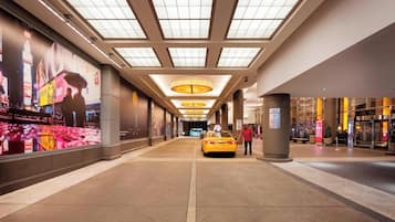 A corridor with a yellow taxi, a large advertisement on the left, and a pillar with a sign.