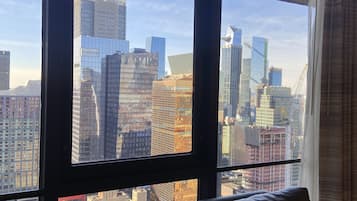 A room with a large window offering a view of a city skyline with various buildings, including a prominent skyscraper.