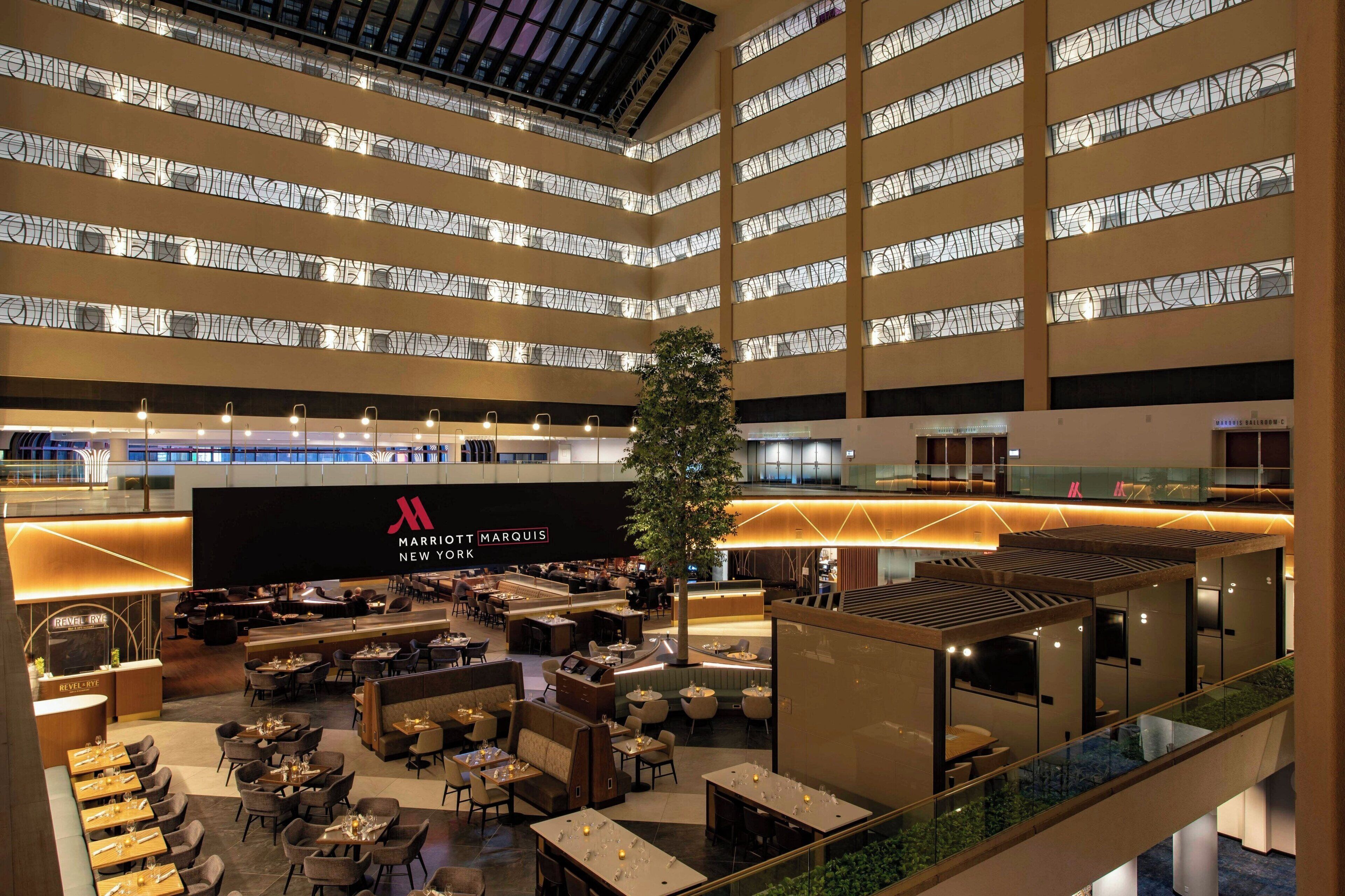 A multi-level hotel lobby with a large Christmas tree, seating areas, and a prominent hotel sign.