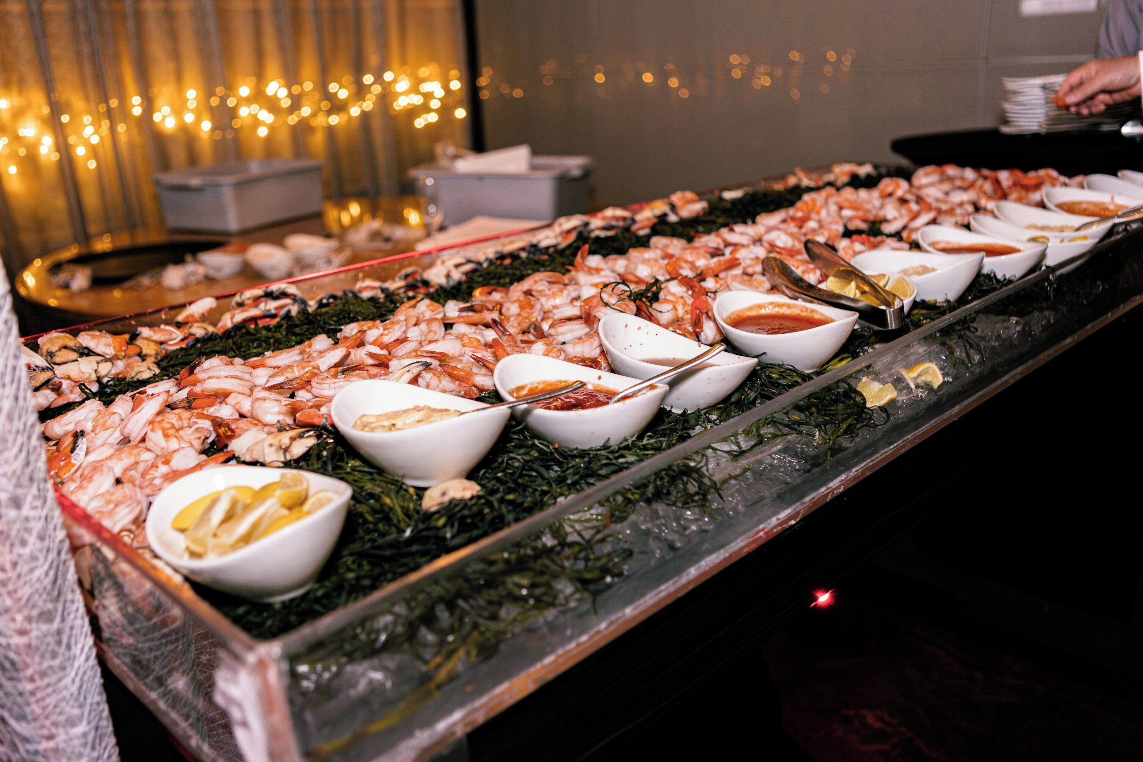 A seafood buffet with various dishes and sauces.