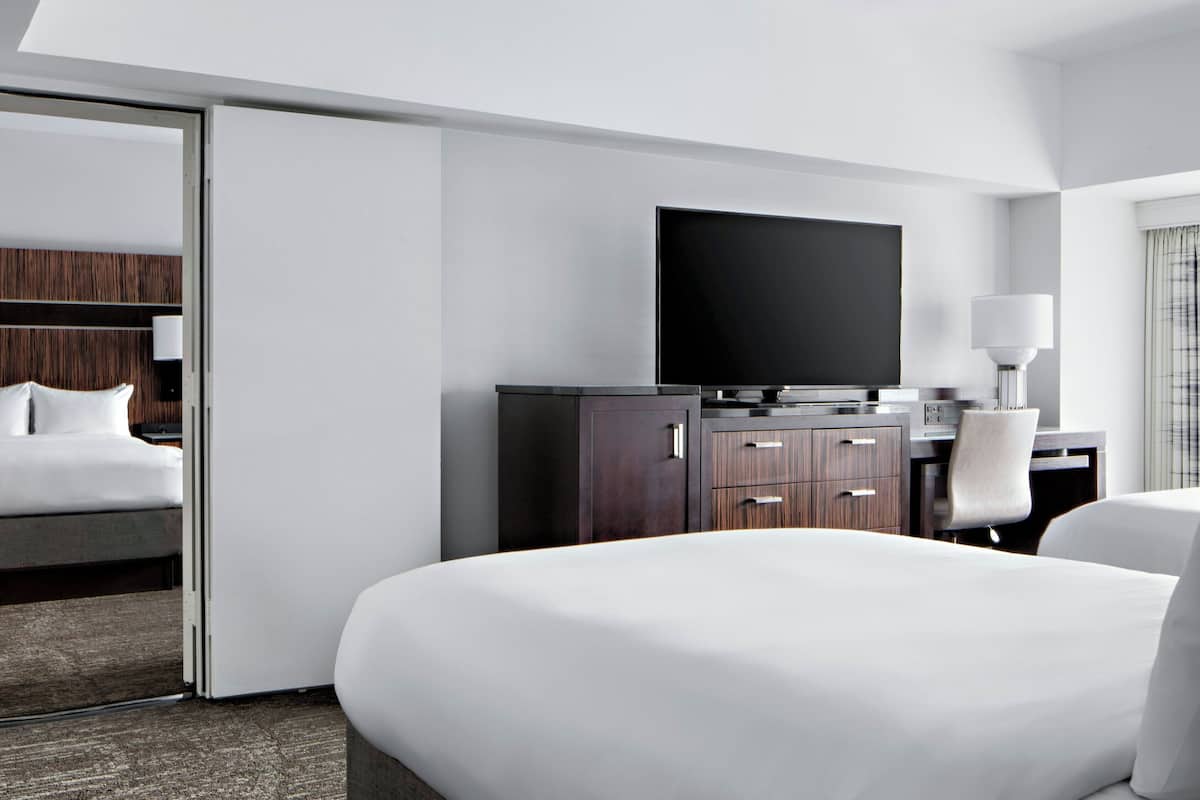 Een hotelkamer met een bed, een bureau met een computer, een televisie en een kledingkast.