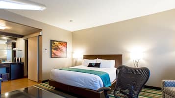 A hotel room with a bed, a chair, a desk with a computer, and a mirror.