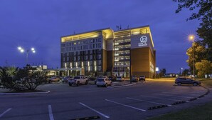 A hotel with a modern design, featuring a large parking lot and multiple vehicles parked. - Hotel Blackfoot (Calgary)