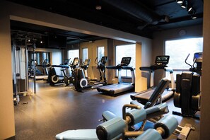 Een fitnessruimte met loopbanden, elliptische trainers en krachttrainingsapparatuur.