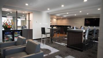 Un moderno vestíbulo de hotel con zona de estar, un pequeño bar y una cocina.