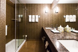Een moderne badkamer met een douchecabine van glas, een ruim wastafelmeubel met meerdere wasbakken, en een spiegel.