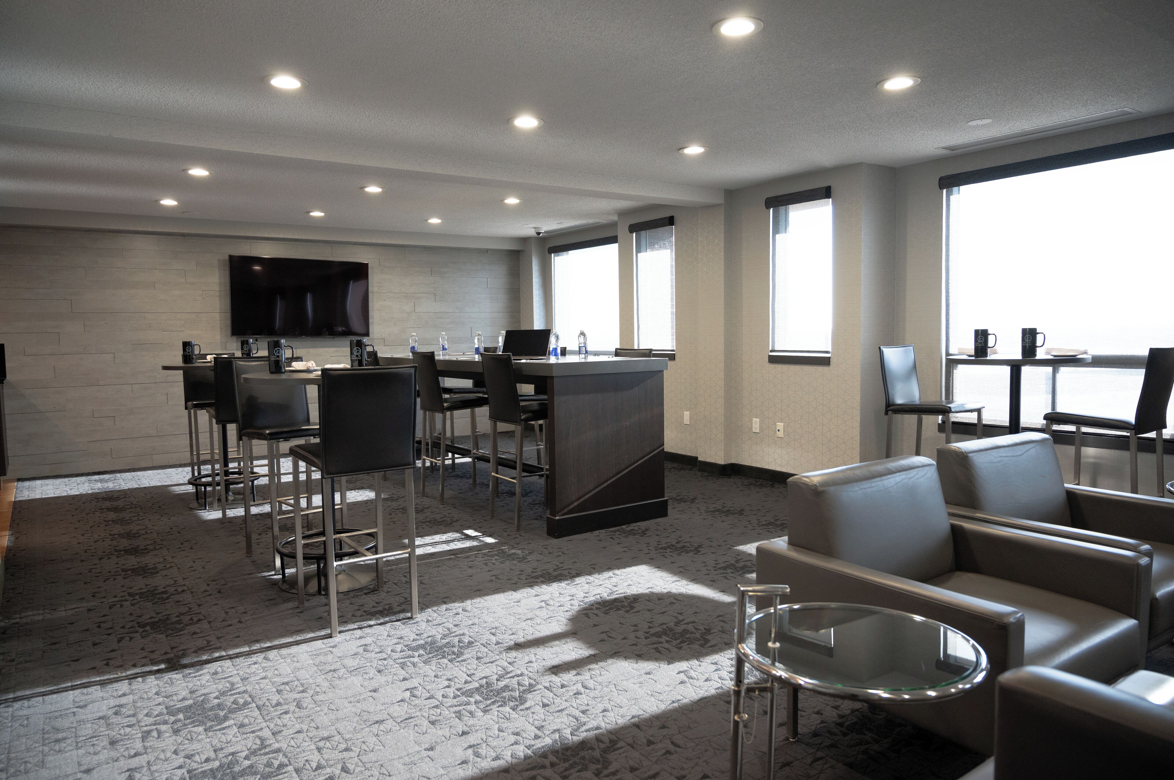A modern hotel lobby with a bar area, seating, and a large TV screen.