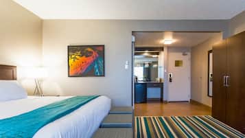 A hotel room with a bed, a desk, a mirror, and a wardrobe.