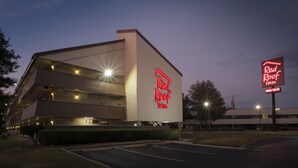A Red Roof Inn with a prominent red sign, a parking lot, and a building with multiple floors and balconies.