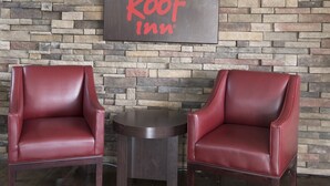 Two leather armchairs, a small round table, and a wall with a sign reading 'Red Roof Inn'.