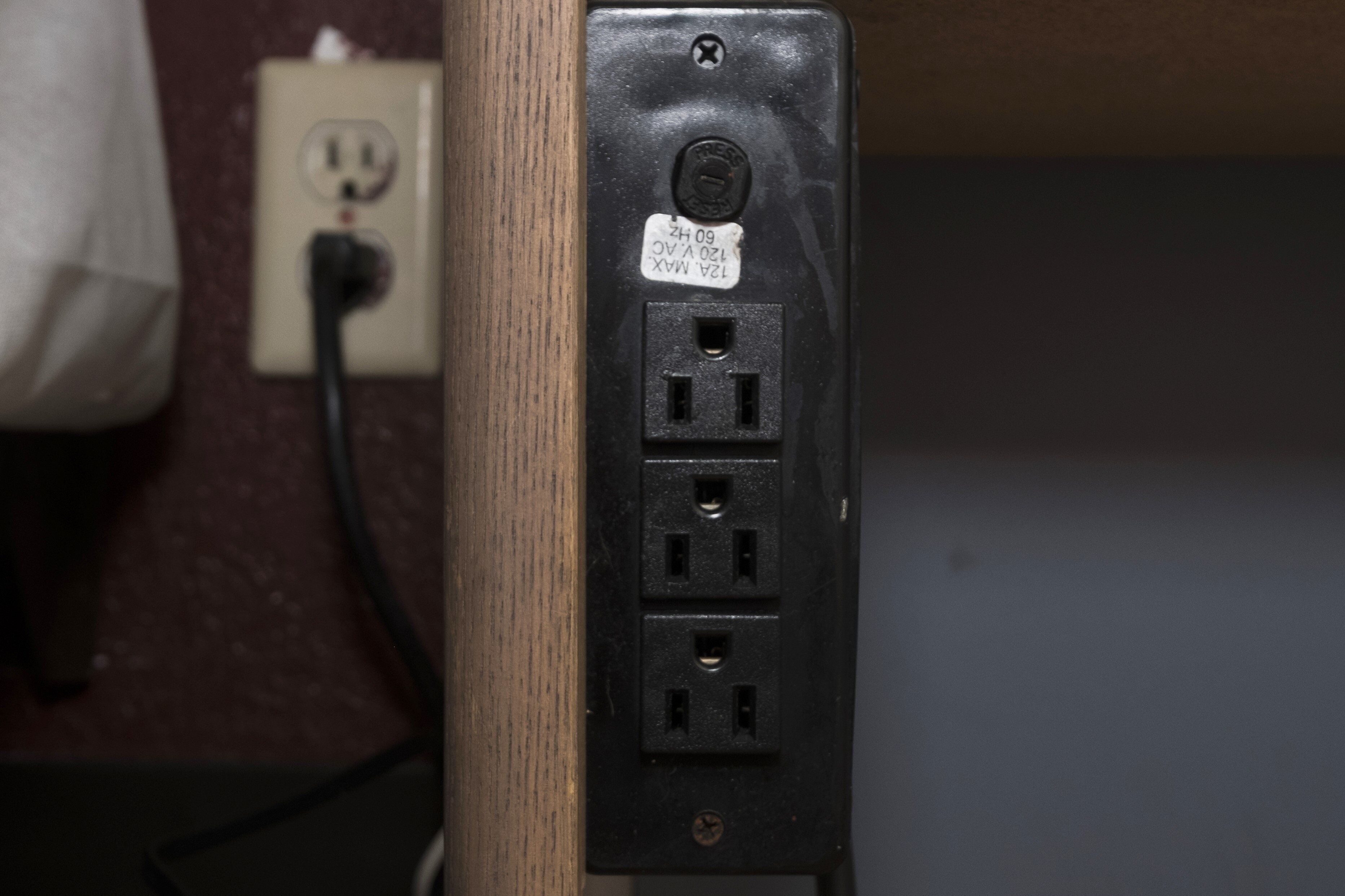 A power outlet with a label, a cable, and a wall socket.