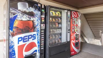 Three beverage vending machines, one with a Pepsi logo, another with a Coca-Cola logo, and a third with a variety of snacks.