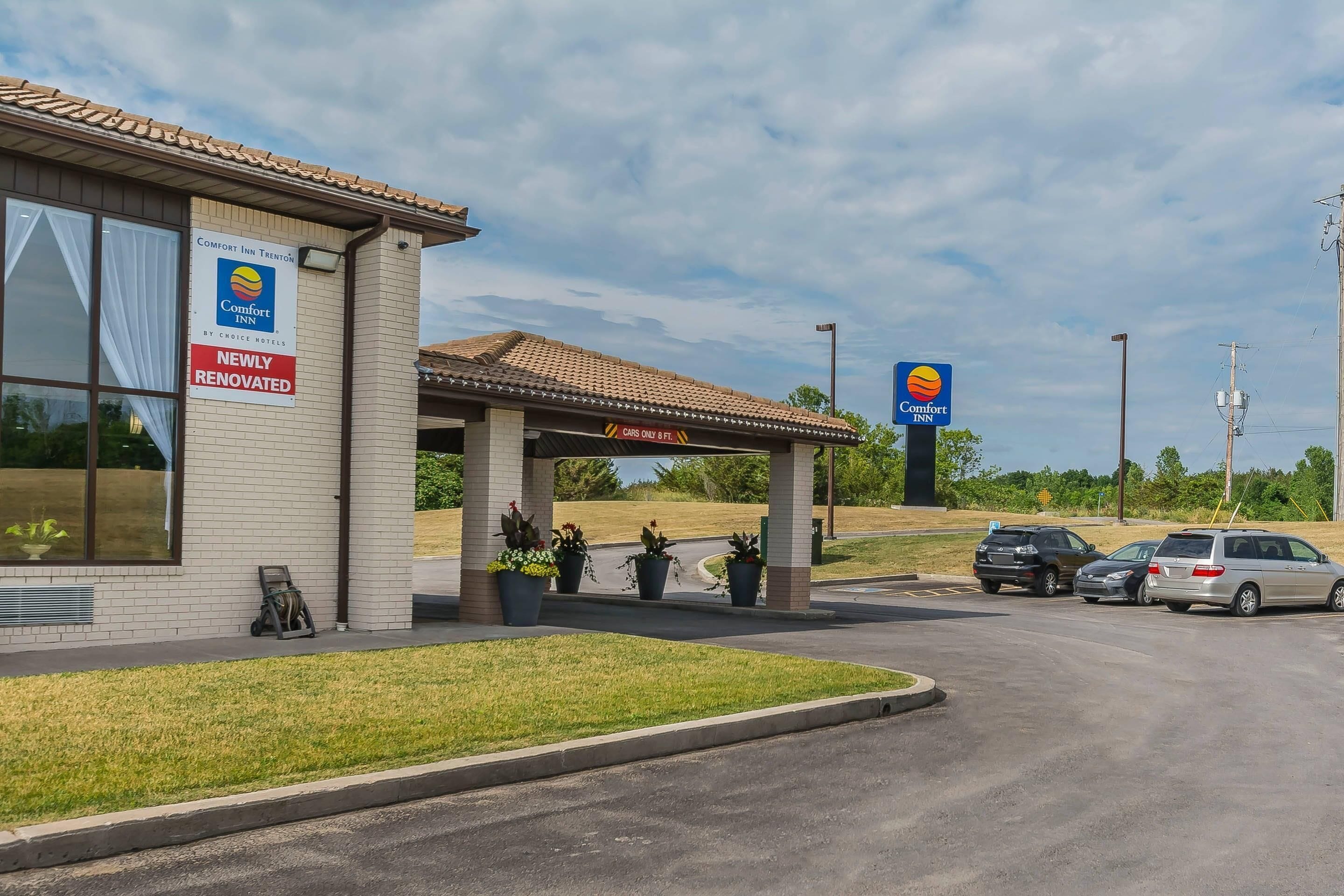 Een Comfort Inn met een vernieuwd bord, een overdekte parkeerplaats en een heldere lucht.