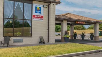 Un bâtiment de la chaîne Comfort Inn, avec une pancarte indiquant « RÉNOVÉ RÉCEMMENT », un espace de stationnement couvert et des plantes en pot.