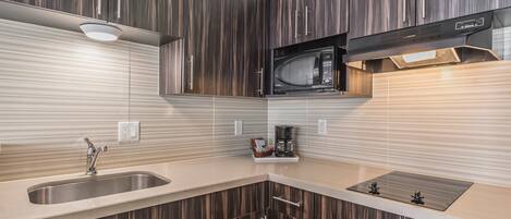 Una cocina moderna con microondas integrado, cafetera y lavamanos.