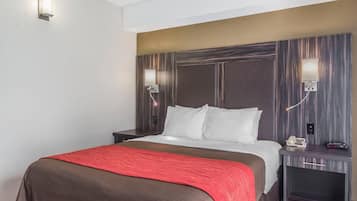 Une chambre d’hôtel comprenant un lit, des tables de chevet, une petite table, une lampe fixée au mur et un téléphone.
