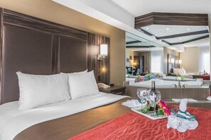 A hotel room with a large bed, a bedside table with a lamp, a mirror, and a view of the bathroom. - Comfort Inn Trenton (Quinte West)