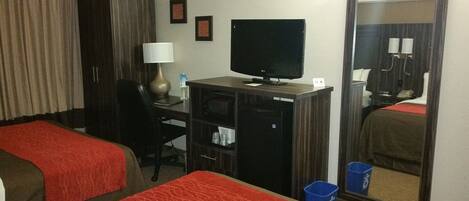 A hotel room with two beds, a desk with a computer, a mirror, and a wardrobe.