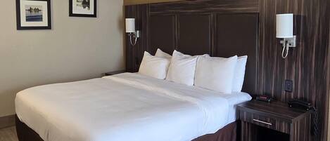 Habitación de hotel con una cama grande, una mesita de noche con teléfono y dos lámparas de pared.