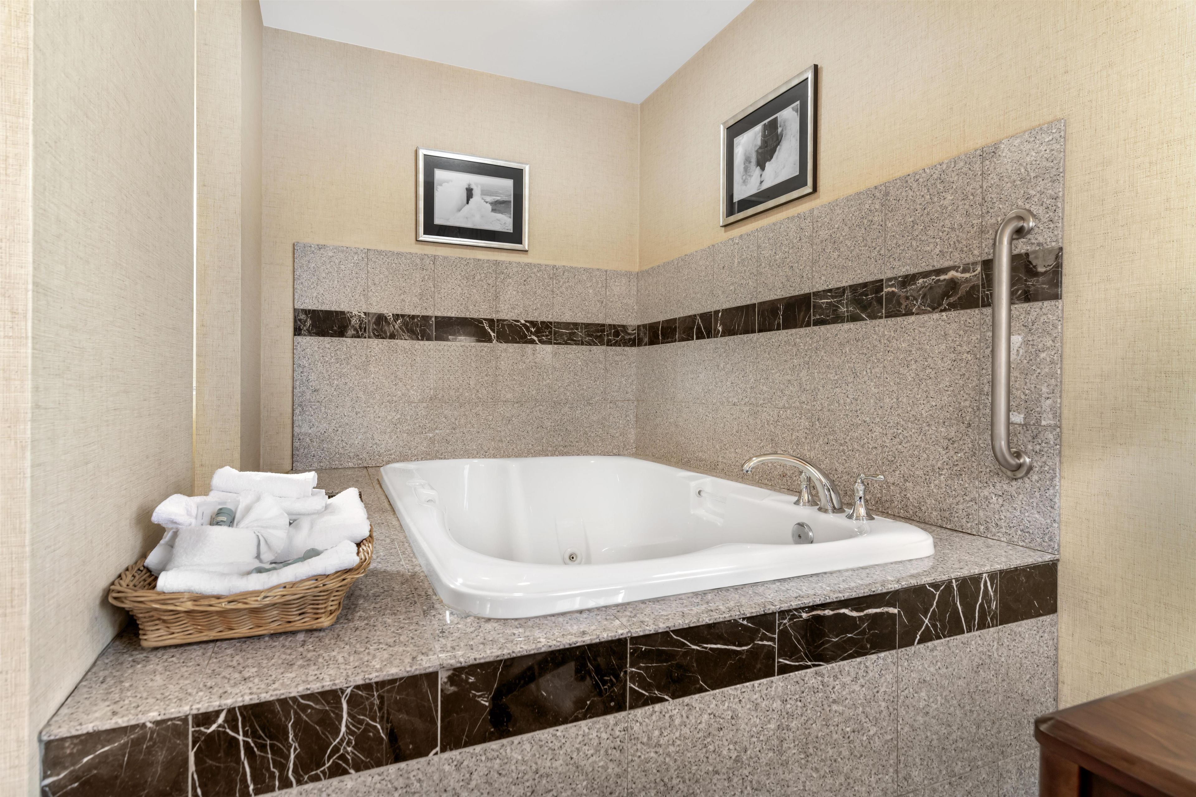 A modern bathroom with a freestanding bathtub, a marble countertop, and a wall-mounted handrail.