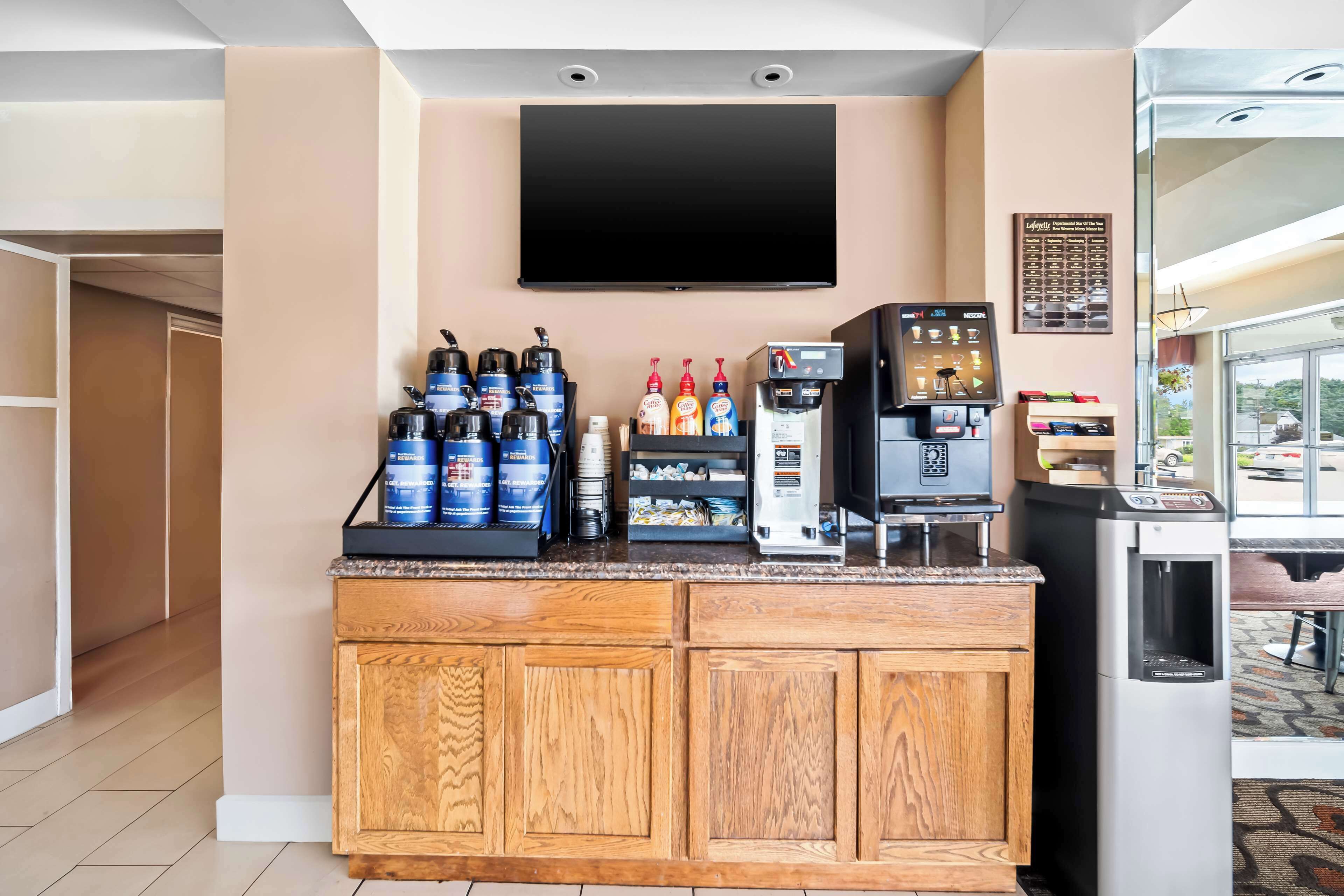 Una zona de bar con televisor de pantalla plana, dispensadores de bebidas y una cafetera.