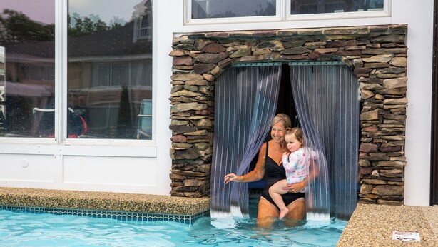 Une piscine avec un mur en pierre et une fenêtre.