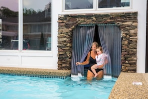 A swimming pool with a stone wall and a window.
