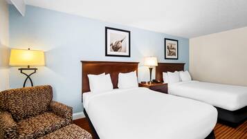 A hotel room with two beds, a chair, and two wall-mounted lamps.