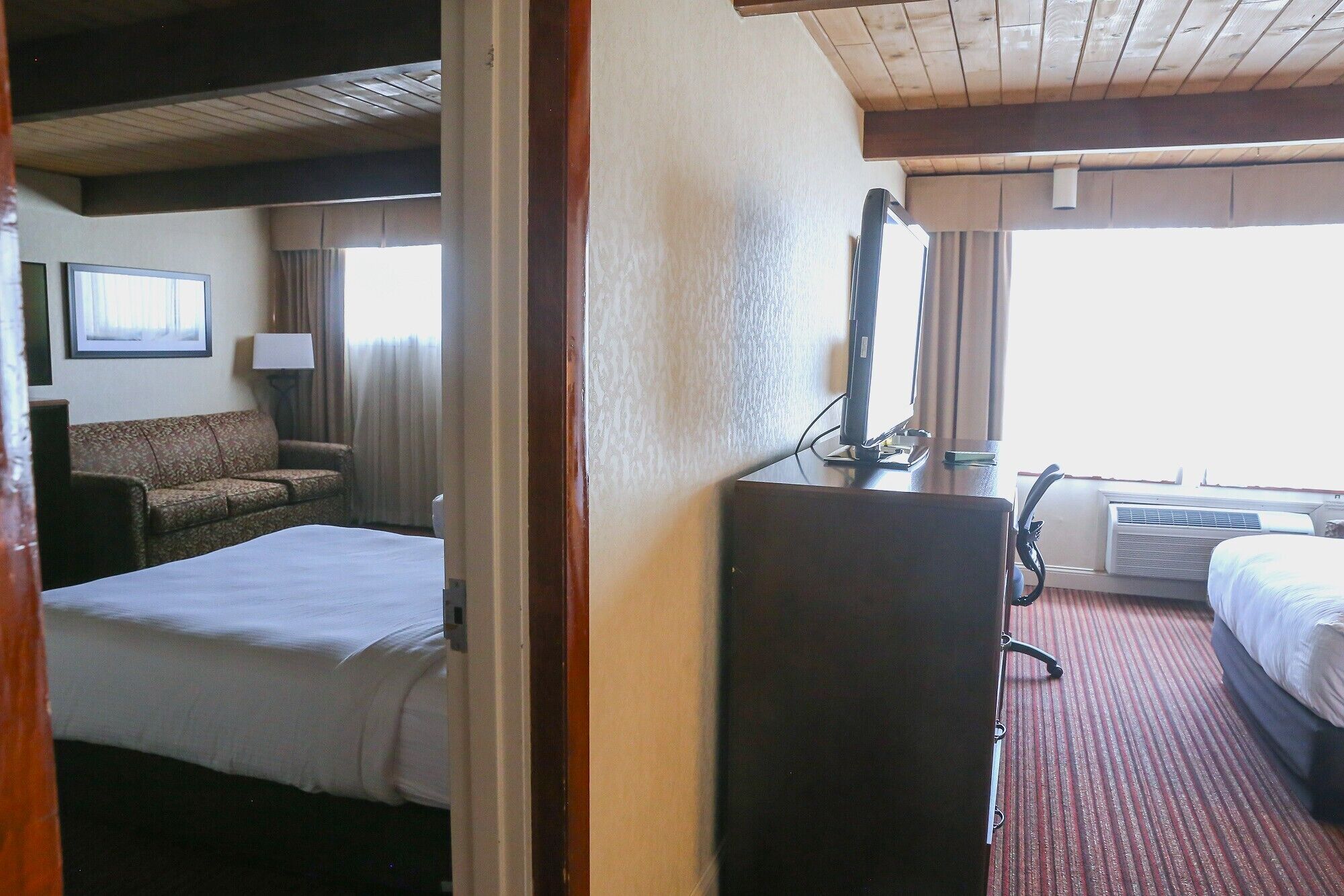 A hotel room with a bed, a desk, a chair, and a television.